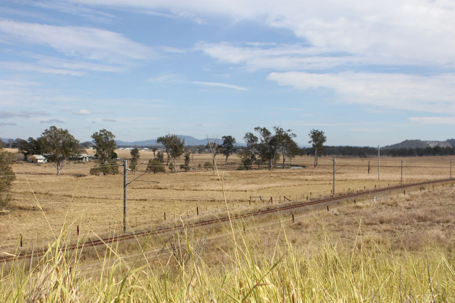 Railway tracks crossing the Curra landscape with homes scattered in the distance